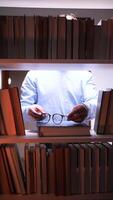 A man is looking at a book shelf with glasses video
