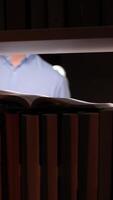 vertical Open book illuminated by flashlight in dark library with man reading video
