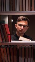 vertical Priest reading holy book in the library surrounded by bookshelves video