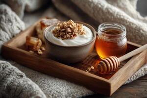 A bowl of creamy yogurt is topped with crunchy granola and drizzled with golden honey, set on a wooden tray surrounded by a soft blanket photo