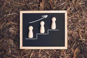 Three wooden figures are on a chalkboard with a line going up photo
