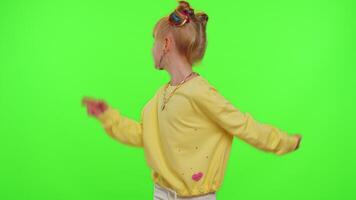 Young Blogger Concept. Cheerful teen school girl kid dancing at camera filming using phone at home on chroma key background, creating her trendy content on a mobile app to share on social media. video