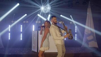 Musical band group playing song performing on concert musician stage with lights. Singer vocalist girl, saxophonist sax, dj man. Music actors dancing, singing at rehearsals preparing for performances. video