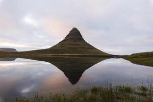 Kirkjufell mountain on the Snafellsnes Peninsula in west Iceland, stands majestically with its reflection mirrored in the still waters below photo