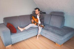 Man relaxes and plays guitar in a quiet room photo