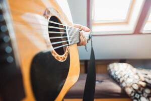 Close-up perspective of an acoustic guitar being played, with fingers pressing the fretboard, capturing the warmth of natural wood, the resonance of the strings photo