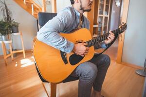 Alone in the middle of a sunlit room enjoys playing a beautiful wooden acoustic guitar and composing new songs. Immersed in the sweet tones of the guitar. Music that heals the soul photo