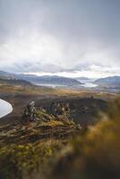 Lone hiker climb on the end of The Horn mountain on Snaefellsnes peninsula in Iceland as golden light from the setting sun illuminates the rugged volcanic terrain below photo