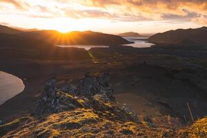 male stands on the end of The Horn mountain on Snaefellsnes peninsula in Iceland as golden light from the setting sun illuminates the rugged volcanic terrain below. Stand on the edge photo