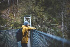 Thoughtful hiker pauses on a suspension bridge deep in Oslo Marka, wrapped in autumn quiet and forest air, blending stillness with scenic exploration. Enjoying view photo