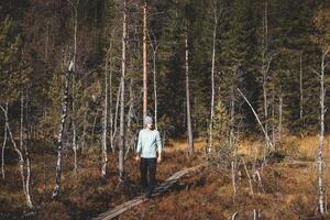 Adventurer walks on a narrow wooden trail in Oslo Marka, surrounded by golden autumn light and the silent whisper of Nordic wilderness photo