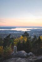 puesta de sol desde Vettakolltoppen pinturas oslofjord en suave pasteles, ofrecimiento un sereno panorama encima el ciudad un inolvidable momento de noruego otoño tranquilidad foto
