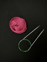 A pink ball of yarn and two knitting needles photo