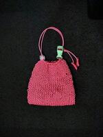 A pink knitted purse with a green cord photo