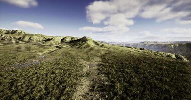 CGI Expansive grassy landscape with rolling hills and distant mountains at sunset video