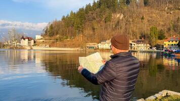 A contemplative traveler, Caucasian male, navigates serene lakeside vistas during Imbolc, embracing unexpected cartographic adventures and natures whispers photo