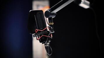 A Professional studio microphone with a pop filter is suspended boom arm and studio lights photo