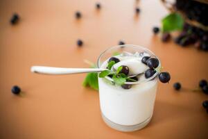 Healthy fermented milk product with berries and spoon on brown background photo