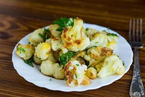 Fried cauliflower with spices and herbs in a frying pan . photo