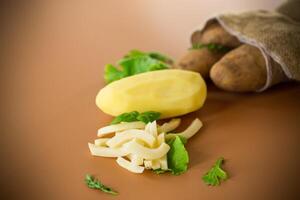 Still life with potatoes in a sack and slices on a brown background photo