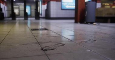 CGI Footprints on the tiled floor of a busy urban subway station at dusk video