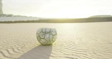 CGI Worn soccer ball abandoned on sandy beach during sunset in serene environment video