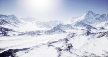 CGI Snow covered mountain range under bright sun in clear blue sky video