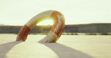 CGI Lifebuoy resting on sand during sunset at a tranquil beach video