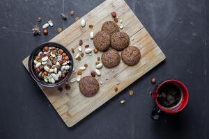 Overhead shot of cookies nuts and coffee on a wooden board against a dark background surface view photo
