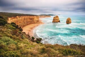 Aerial view of cliffs and beach with rock formations in the ocean under a cloudy sky landscape scene photo