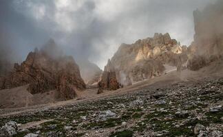 View of rocky mountains with clouds and fog covering the peaks on a cloudy day in the wilderness photo