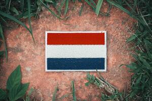 Top view of eco friendly Netherlands flag hand stitched with natural fabric, placed on ancient stone surrounded by leaves. Highlighting patriotism and sustainability in Europe. photo