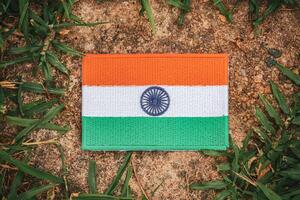 Top view of eco-friendly Indian flag made from hand-stitched fabric, placed on ancient natural stone surrounded by leaves and grass. Representing love for India, Asia. photo