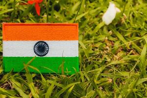 Eco friendly India flag, hand embroidered with natural fabric, placed on green grass with soft white and red flower petals. Left composition with copy space for Middle East Green Initiative themes. photo