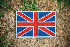 Top view Union Jack flag in eco style on natural stone with grass and leaves. A symbol of the UK s cultural pride and green awareness, ideal for Earth Day or climate themes. photo