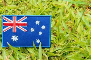 Australian eco flag made of embroidered thread and cloth, standing on natural grass. Positioned left with space on the right, ideal for Earth Day and green topics. photo