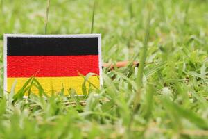 German flag made of eco-friendly thread and cloth, leaning on natural grass with space for text on the right. Promotes Earth Day, sustainability, and climate awareness. photo