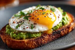 Satisfying breakfast features a sunny-side-up egg atop creamy avocado spread on toasted bread, garnished with spices and herbs photo