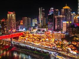 Chongqing, China - APR 02, 2025-Aerial Night view Cityscape of the famous downtown shopping complex Hongyadong with illuminated bridge and highrise building. photo