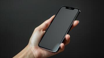 Hand holding a black smartphone with blank screen photo