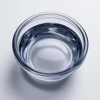 A glass bowl filled with water on a white surface photo