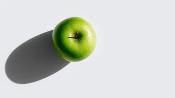 A crisp green apple is placed on a smooth surface, creating a gentle shadow while illuminated. photo