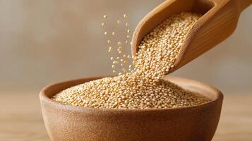 Amaranth seeds are poured from a wooden scoop into a bowl, showcasing natural grains. photo