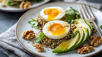 Quinoa bowl features poached eggs, fresh avocado, spinach, and walnuts for a nutritious breakfast. photo