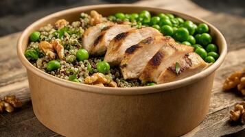 A nutritious bowl featuring grilled chicken, quinoa, green peas, and walnuts on a rustic table. photo