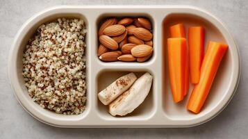 A nutritious snack tray holds quinoa, mixed nuts, carrots, and banana slices ready to eat. photo