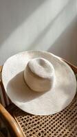 Straw Hat Resting on a Wooden Chair in a Sunlit Corner of a Cozy Room. photo