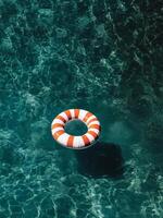 Lifesaver Ring Floating in Clear Swimming Pool Water on a Sunny Day photo
