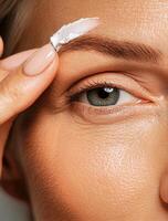 Woman Applying Cream to Brow Area in Bright Indoor Setting photo