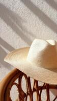 Stylish Straw Hat Resting on a Wooden Chair With Subtle Shadows in a Sunlit Room photo